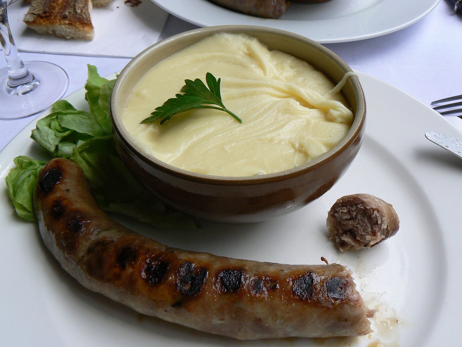 Bol d’aligot servi avec une saucisse grillée