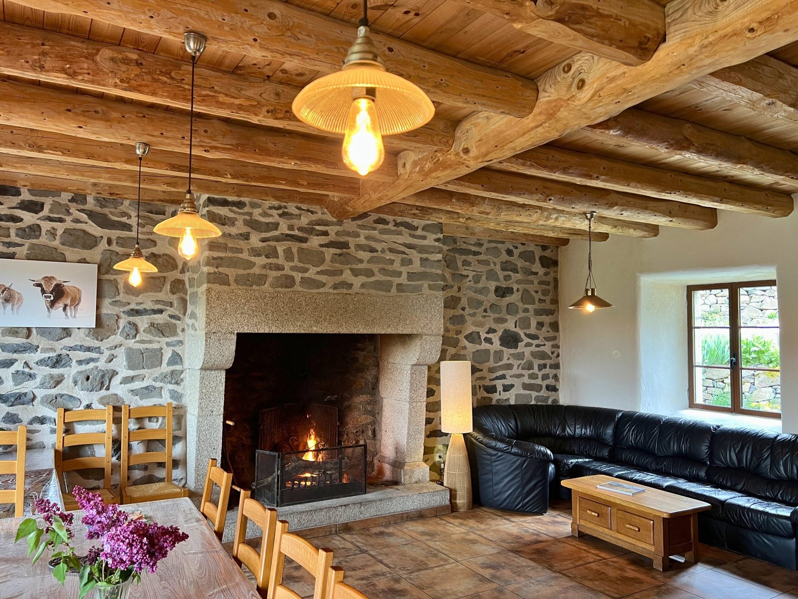 Le salon avec sa cheminée, ses murs de pierre et sa charpente