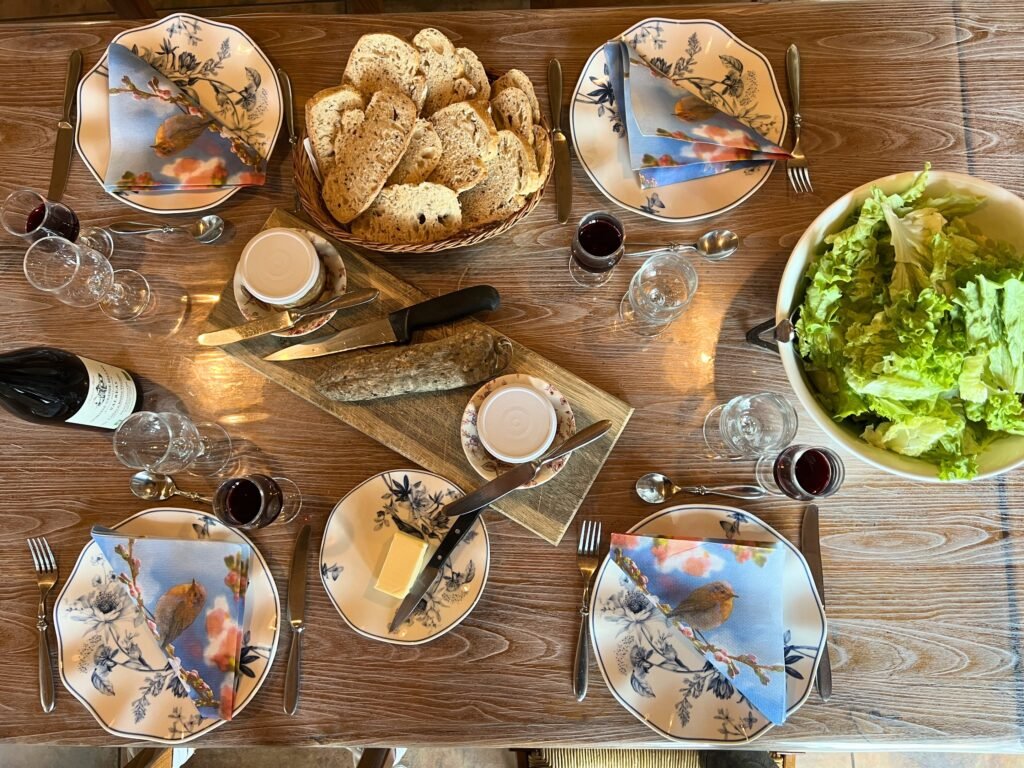 Pain, salade, fromages et vin sur la table d’hôtes